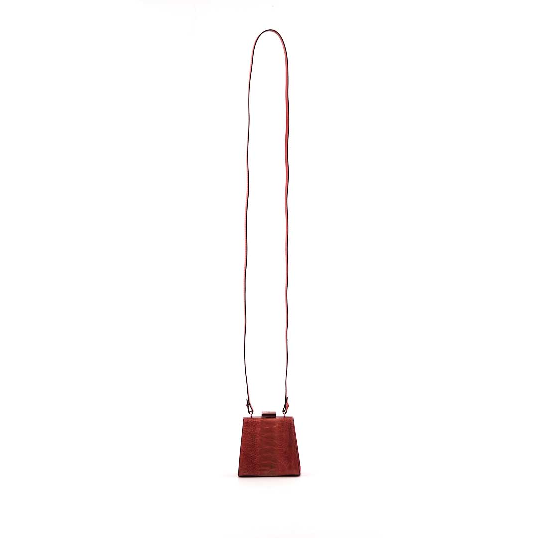 Red handbag with a long strap on a white background