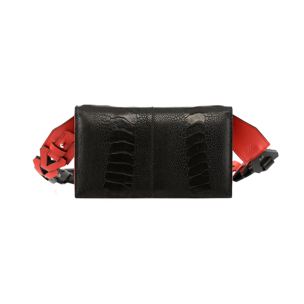A black leather purse with red details on the straps, featuring a compact design and a removable strap.
