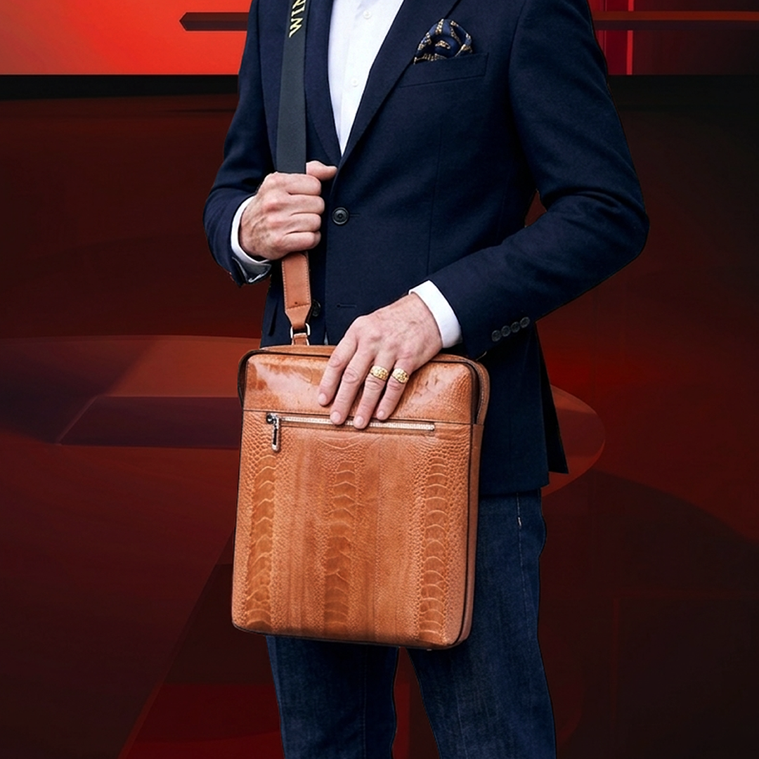 Man holding a brown leather bag against a red background