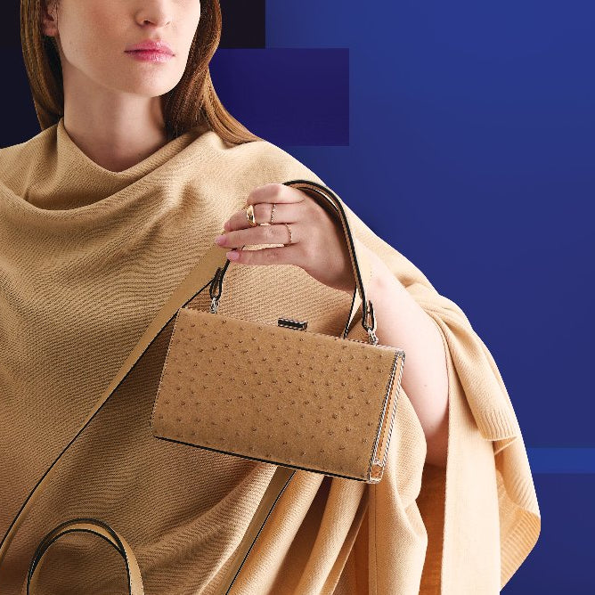 Woman holding a brown handbag against a blue background