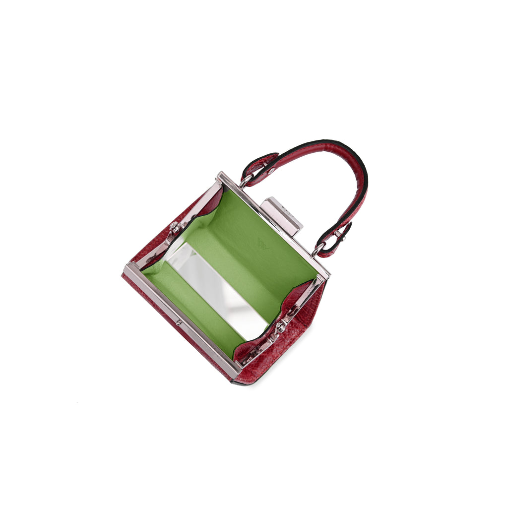 A structured handbag with a glossy red textured exterior, a vibrant lime green interior lining, and a silver-tone metal frame and handle, shown on a plain white background.