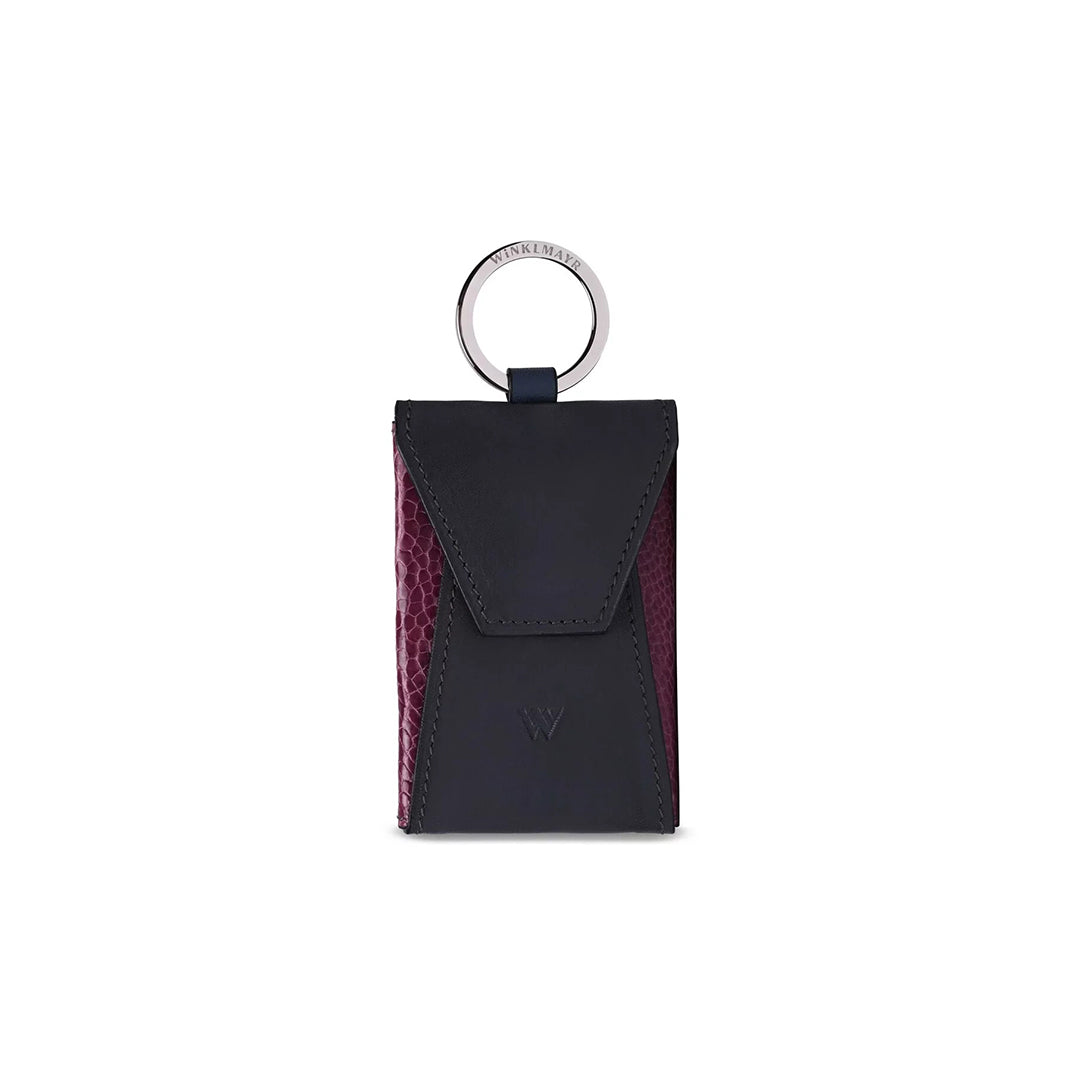 A small black leather purse with a keychain ring on top, featuring a front button closure.