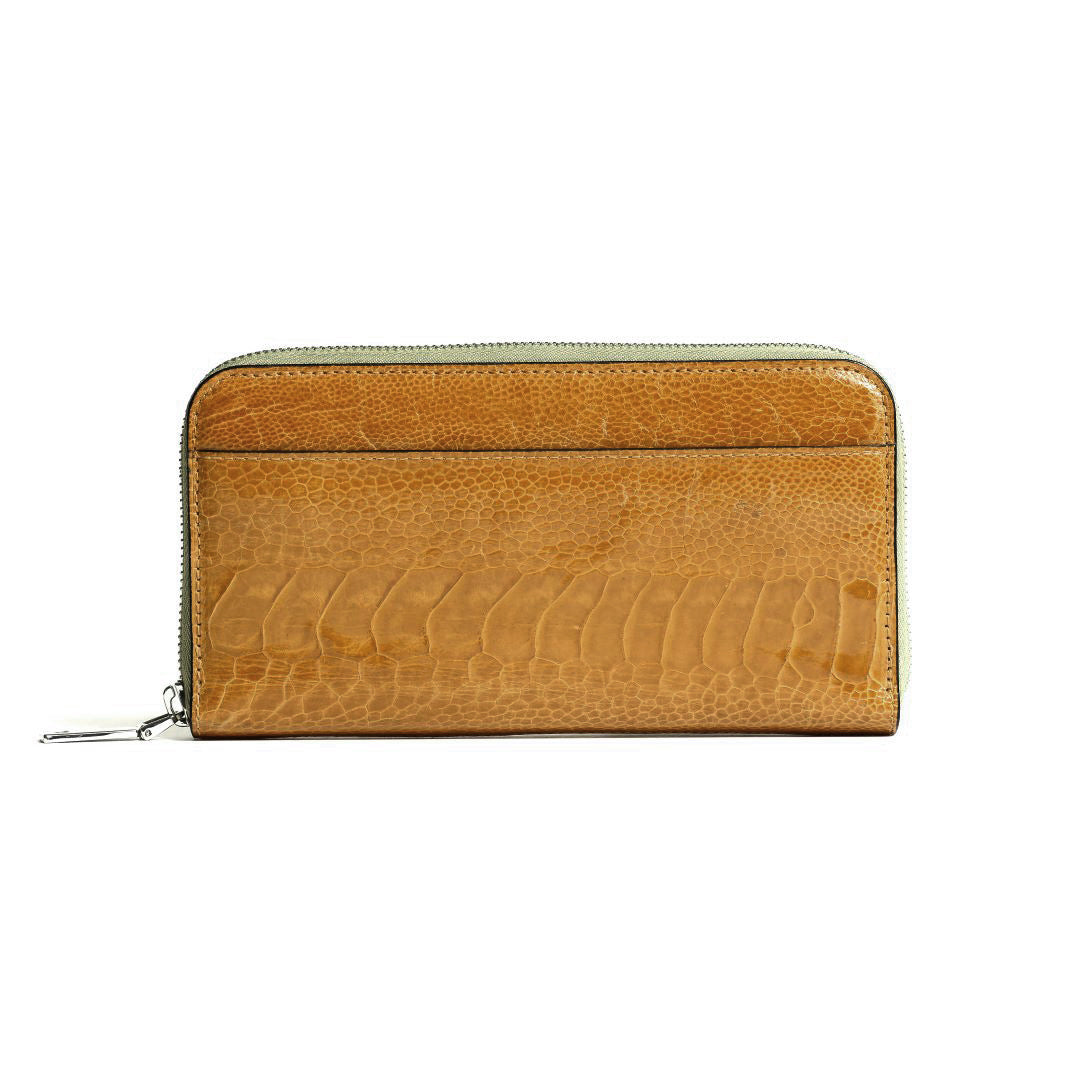 A tan leather zip-around wallet with a crocodile-embossed texture, featuring a light sage green zipper trim and a silver zipper pull, shown against a plain white background.