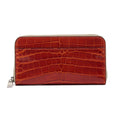 A cognac brown crocodile-patterned leather wallet with a zipper.