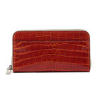 A cognac brown crocodile-patterned leather wallet with a zipper.
