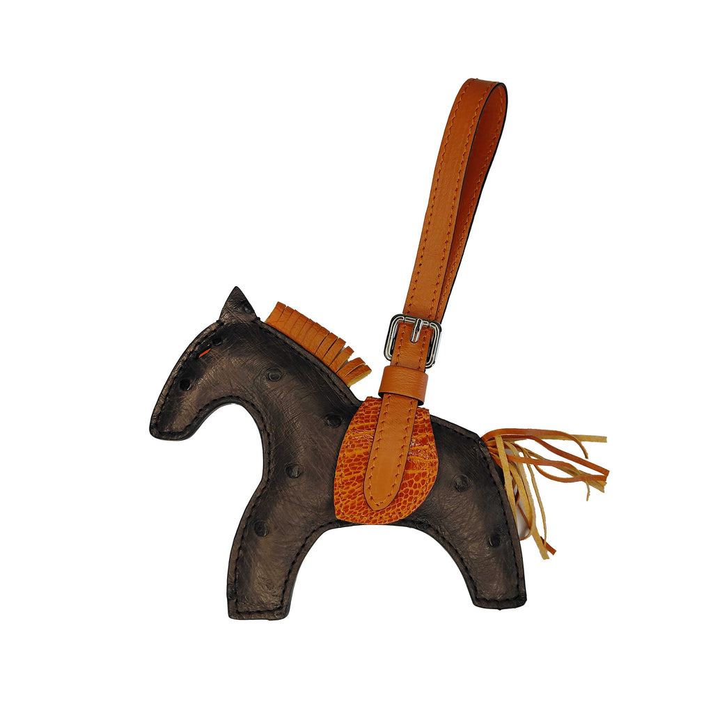 Horse-shaped keychain with brown leather strap and fringes on a white background
